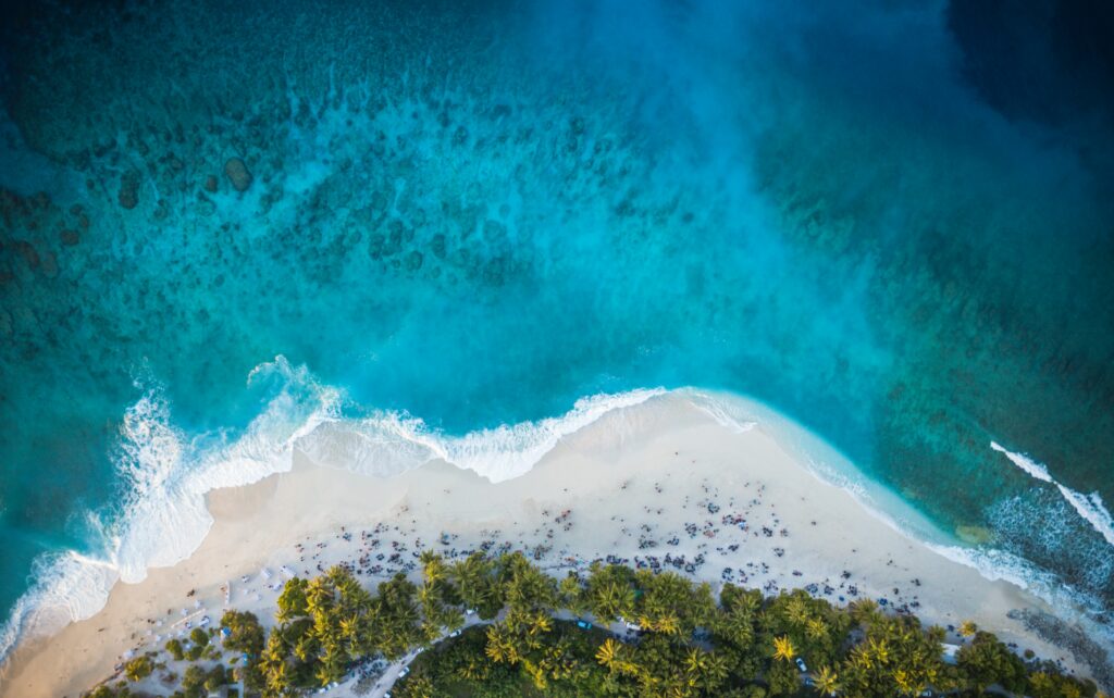 Aerial view of tropical island with palm trees white sandy beach and clear turquoise sea waves background Wallpaper