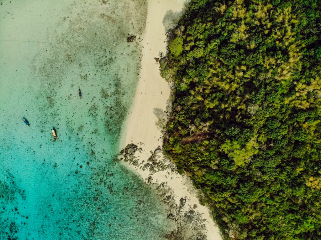 Aerial view of tropical island with lush forest white sandy beach and turquoise ocean waters Wallpaper