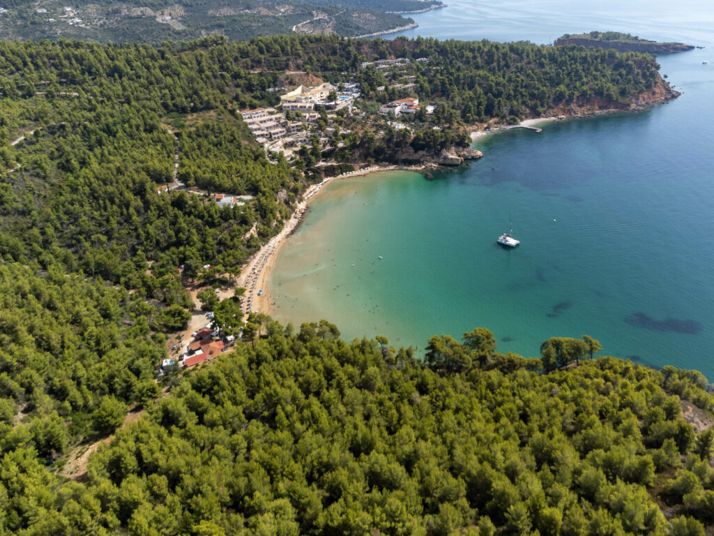 Aerial view of lush tropical island with turquoise sea sandy coast and small boat in calm bay Wallpaper