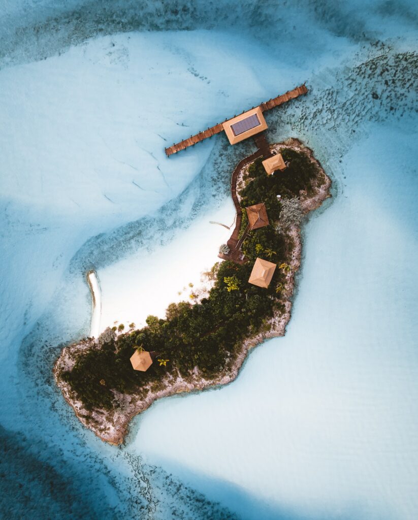 Aerial view of tropical island with wooden huts lush greenery and turquoise ocean waters wallpaper