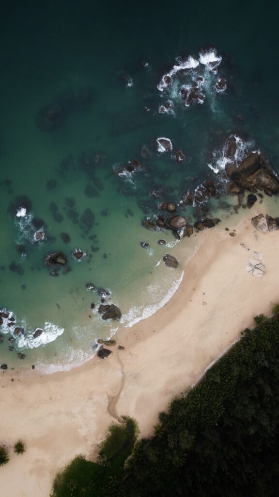 Aerial view of tropical island coast with turquoise waves sandy beach rocks and palm trees Wallpaper