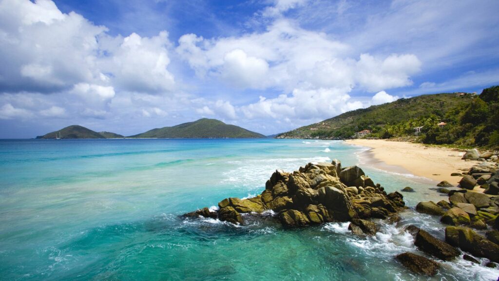 Tropical coast wallpaper with stone formations turquoise surf golden sandy beach and blue sky