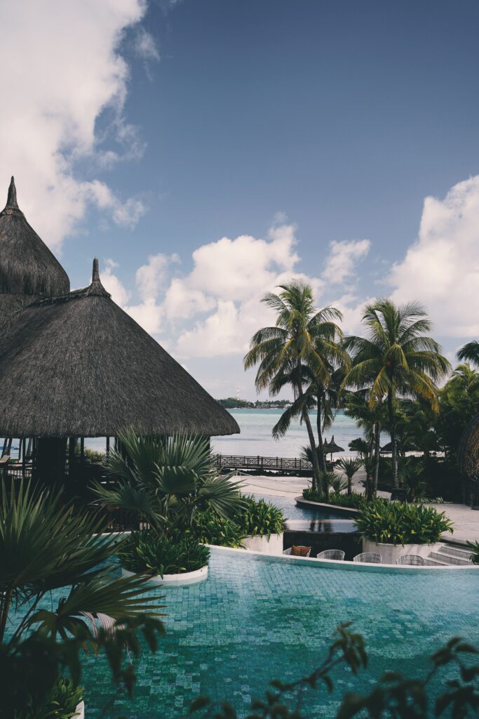Tropical island wallpaper with palm trees turquoise pool thatched huts bright blue sky serene getaway