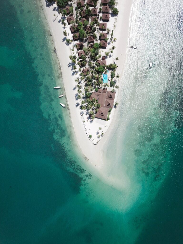 Aerial view of tropical island with palm bungalows boats and turquoise ocean for wallpaper