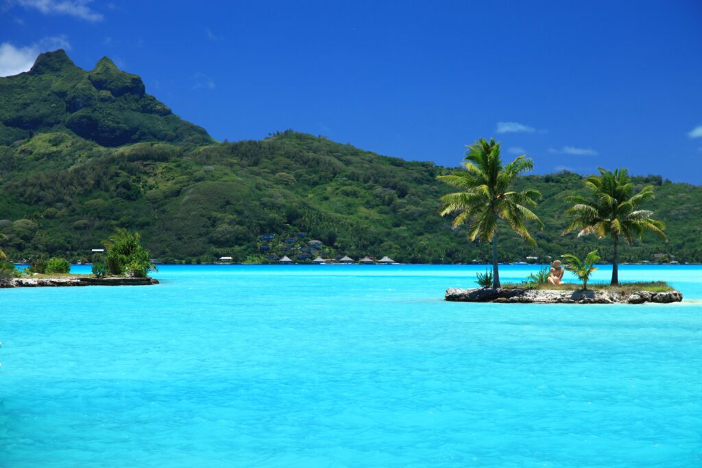 Tropical island wallpaper with turquoise waters lush mountains palm trees and blue sky background