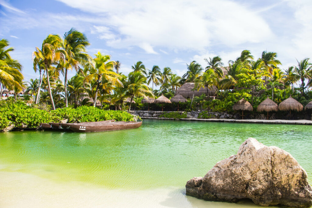 Tropical lagoon with palm trees and thatched huts under a sunny sky peaceful getaway wallpaper