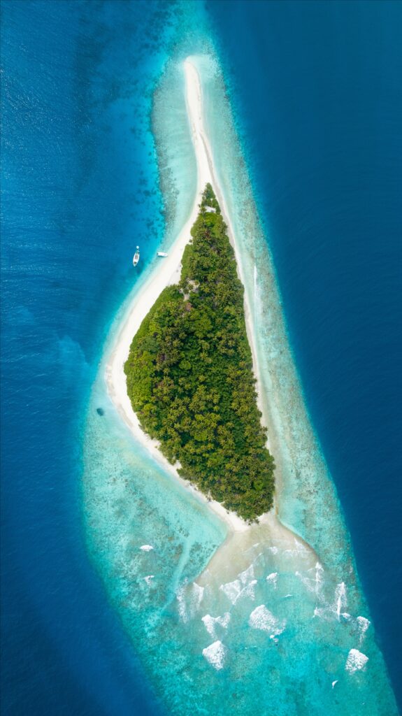 Aerial view of lush tropical island in Maldives with turquoise waters coral reefs and white sands Wallpaper