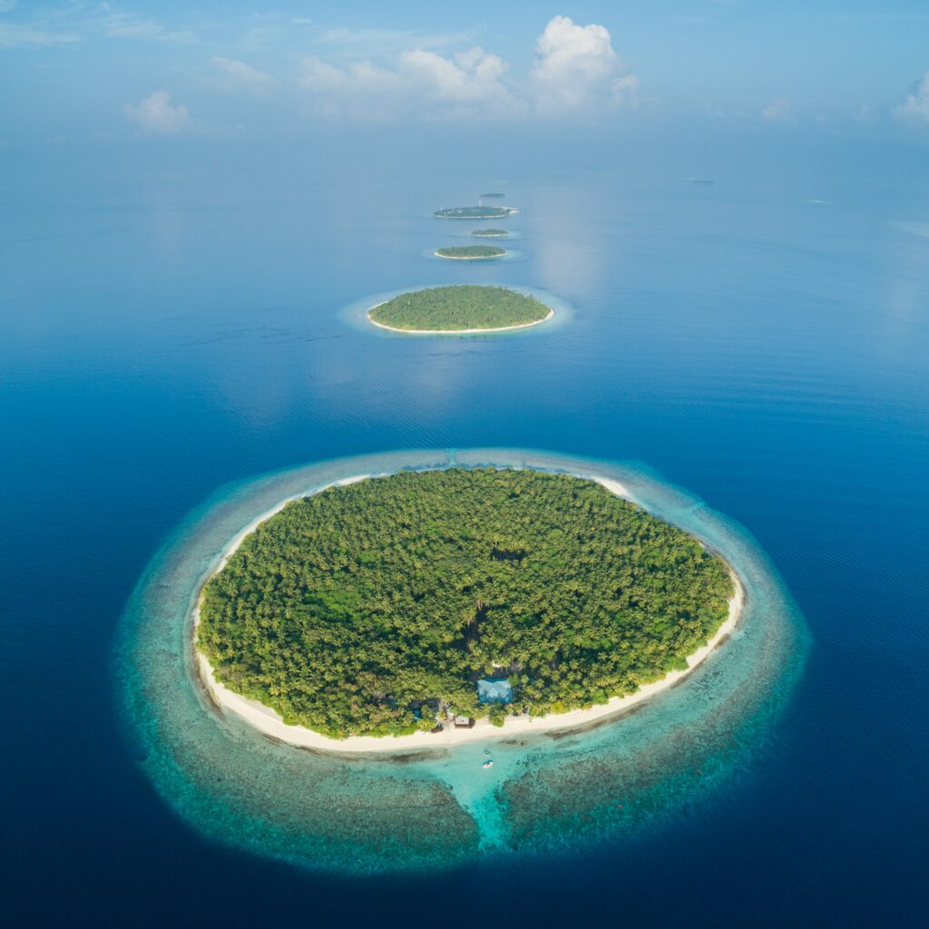 Aerial view of lush Maldivian islands with turquoise waters and vibrant coral reefs under blue sky Wallpaper