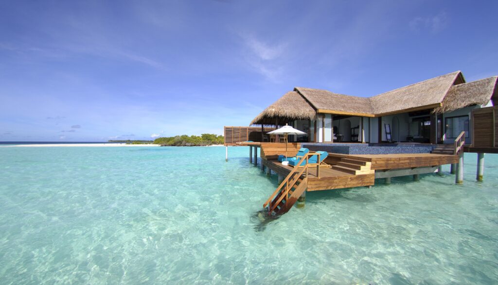 Maldives overwater bungalows with thatched roofs over turquoise water under clear blue sky wallpaper