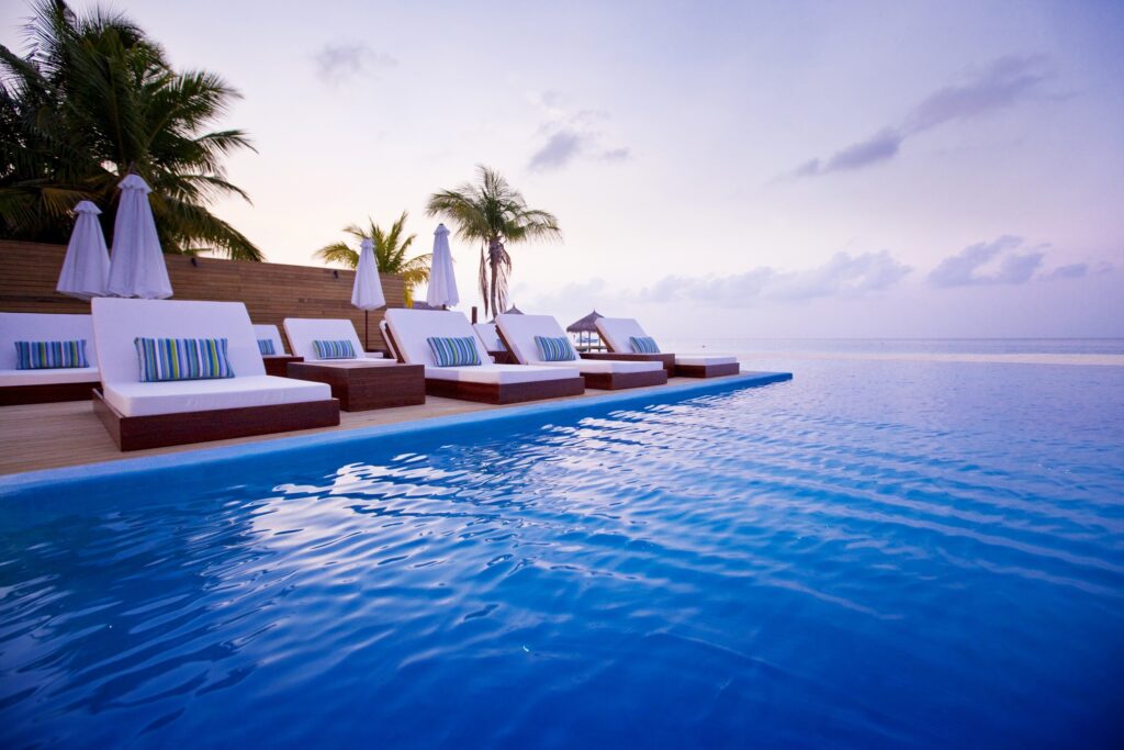 Maldives tropical paradise infinity pool palm trees ocean view pastel sky luxury wallpaper