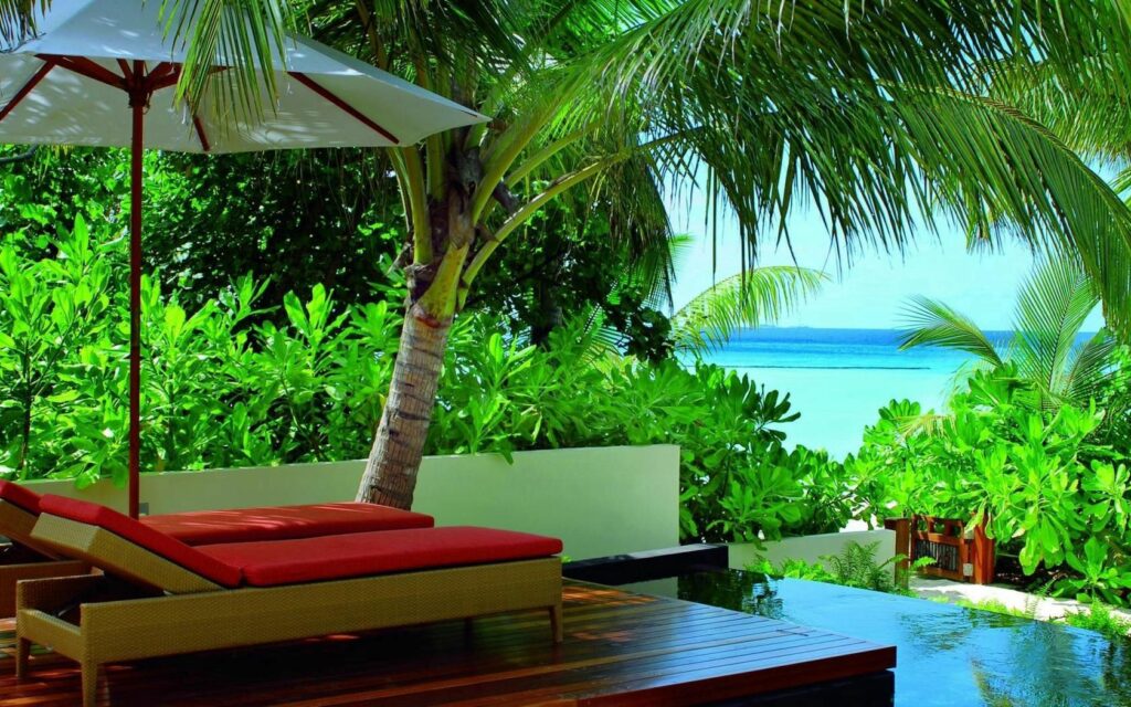 Maldives resort with lush palm trees turquoise pool and ocean view tropical paradise wallpaper