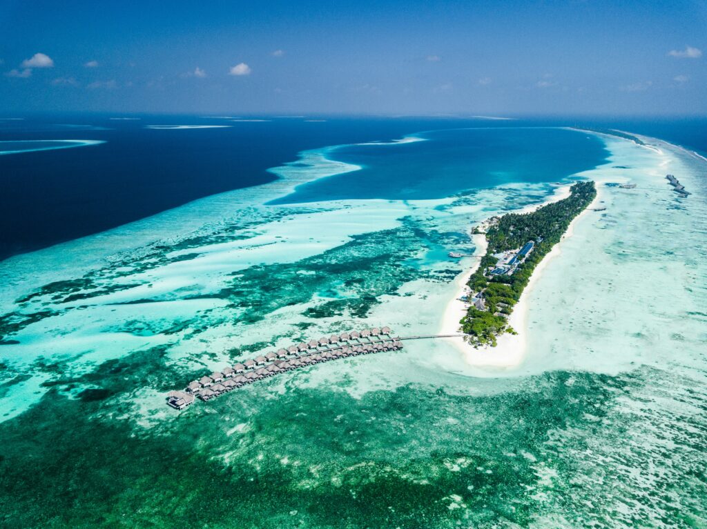 Aerial view of tropical paradise with overwater bungalows turquoise ocean and lush island greenery Wallpaper
