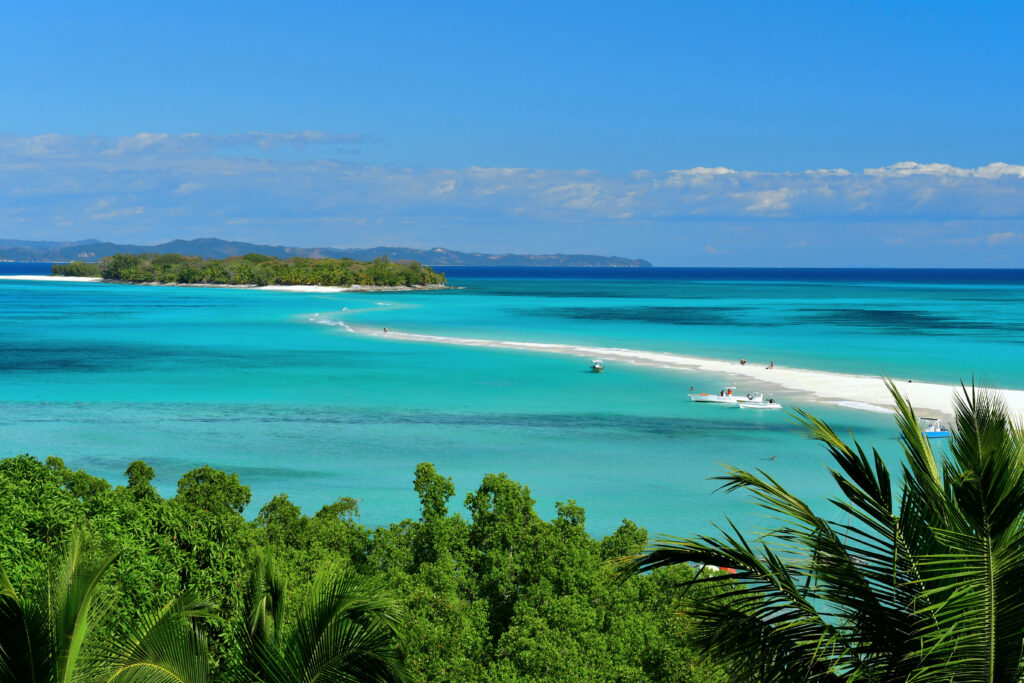 Tropical paradise wallpaper with turquoise waters white sand lush trees and boats by coastline