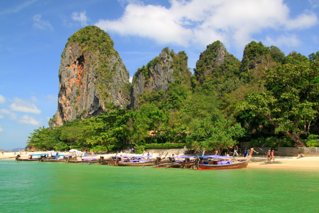 Tropical paradise wallpaper with emerald sea golden beach traditional boats limestone cliffs