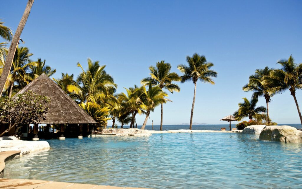 Serene tropical pool with palm trees and thatched bungalow in luxury hotel paradise background Wallpaper