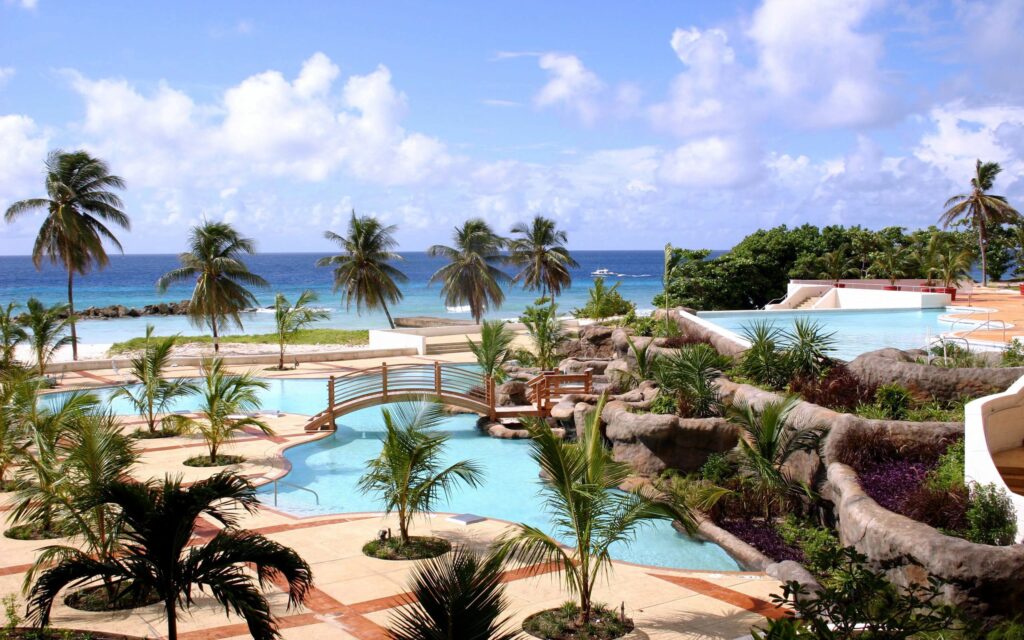 Tropical resort wallpaper with clear pools palm trees lush greenery blue ocean summer paradise