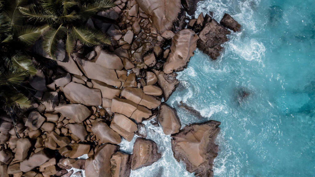 Tropical Aerial View: Rocky Beach & Turquoise Waves Wallpaper