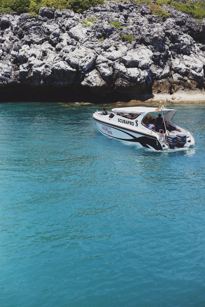 SCUBAPRO dive boat cruising turquoise waters near rugged limestone cliffs tropical ocean adventure Wallpaper