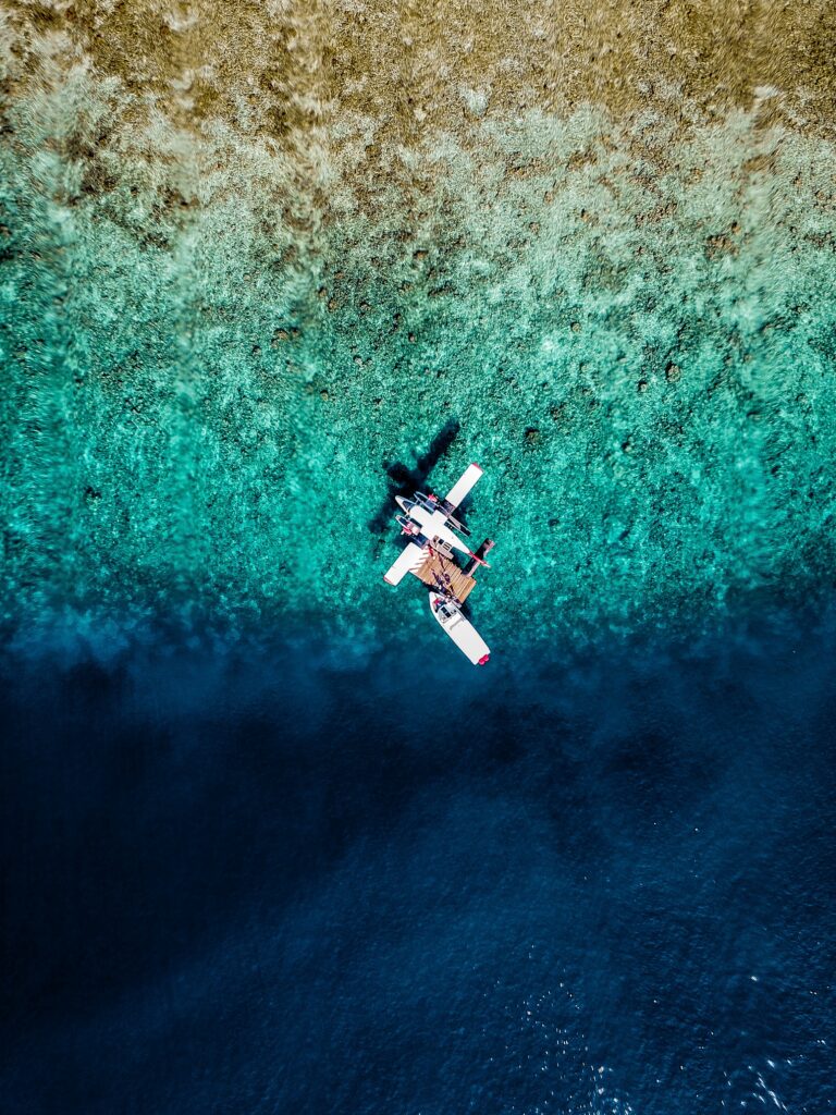 Aerial view of seaplane over turquoise water and vibrant coral reef tropical marine wallpaper background