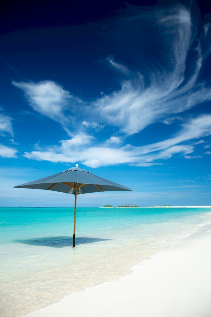 Tropical shore with umbrella in turquoise water and white sand under clear blue sky wallpaper