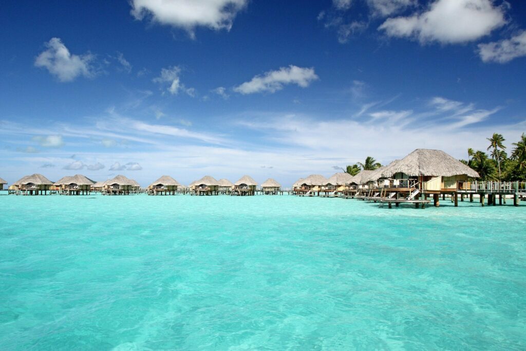 Tropical Turquoise Paradise: HD Wallpaper of Bora Bora Sky and Bungalow Amidst Holiday Vibes