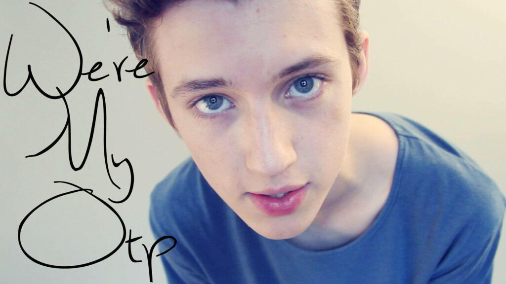 Troye Sivan baby face close-up wallpaper with soft lighting clear blue eyes and handwritten text