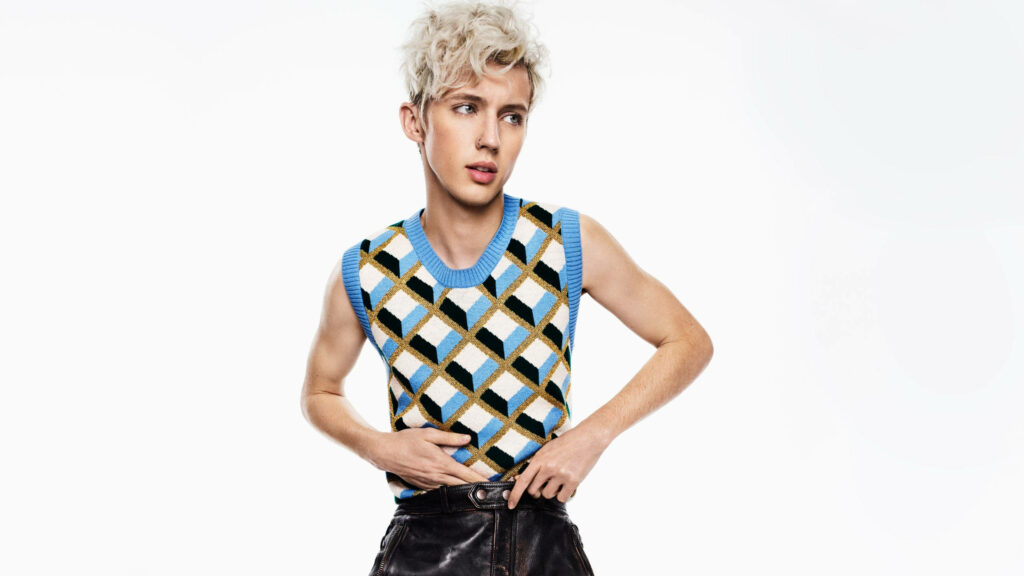 Troye Sivan in stylish blue retro vest confident pose modern fashion white background wallpaper