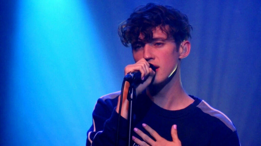 Troye Sivan performing live on stage vibrant blue lighting concert wallpaper background