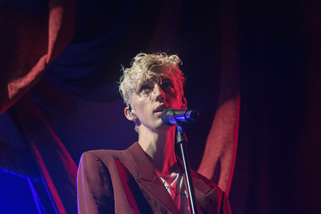 Troye Sivan performing live at ACL in maroon blazer with dramatic lighting concert atmosphere Wallpaper