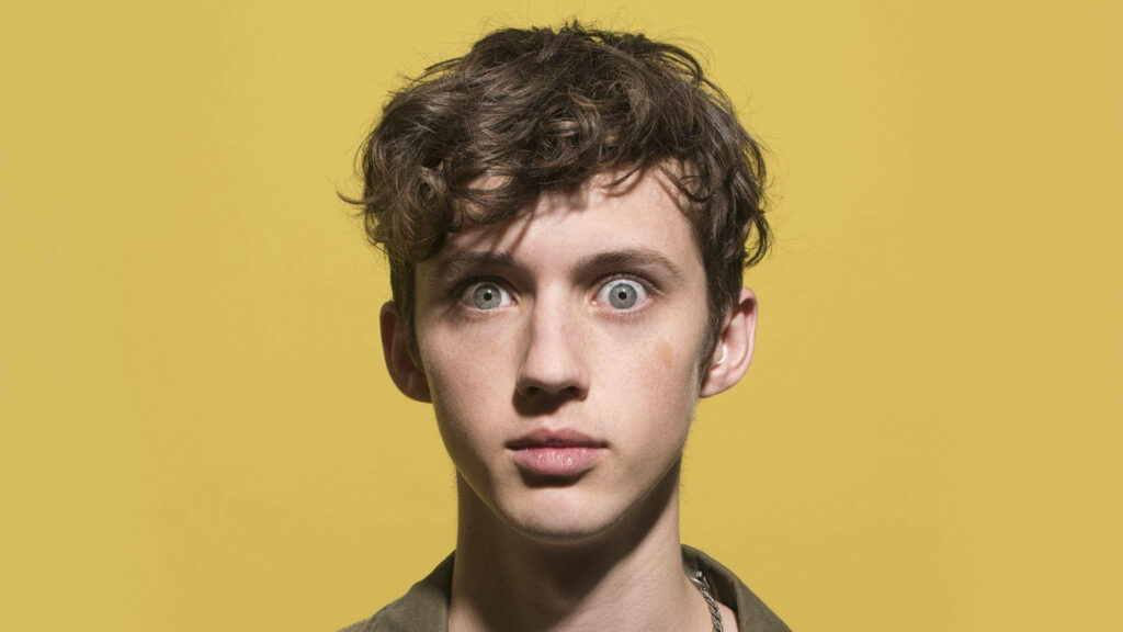 Troye Sivan vibrant yellow background playful quirky expression bright colorful wallpaper image