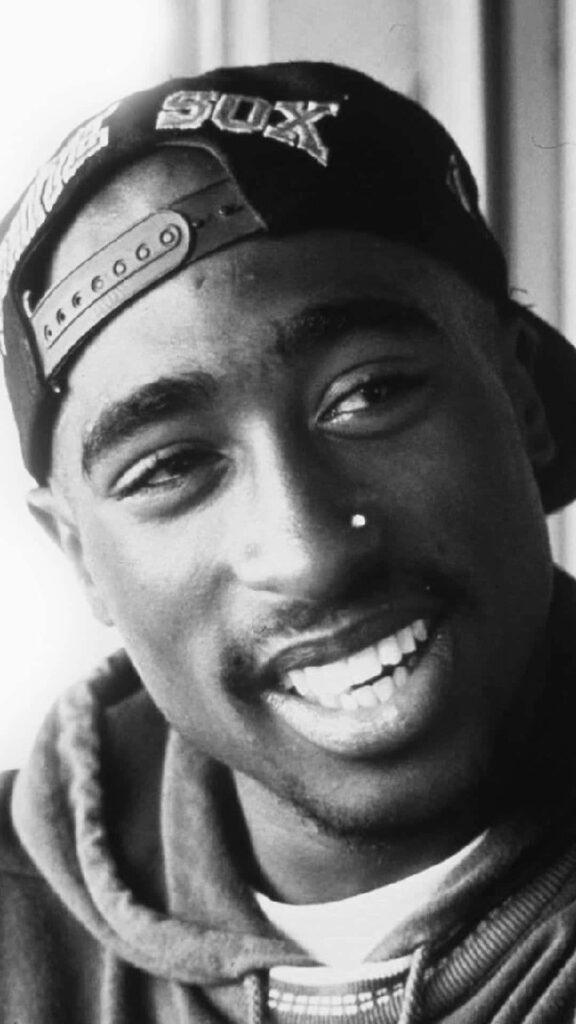 Captivating Portrait: Tupac Shakur's Soulful Smile Illuminates This Monochromatic Up-Close Photograph Wallpaper