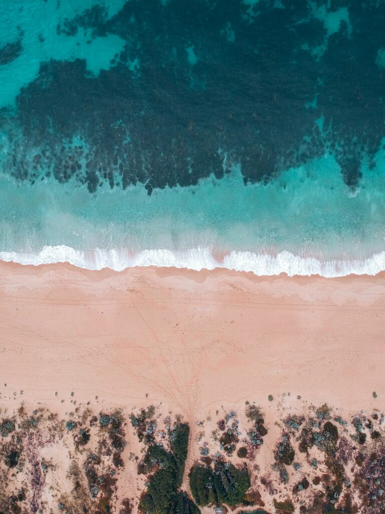 Aerial view of tranquil beach with turquoise sea soft sandy shore and gentle waves natural textures Wallpaper