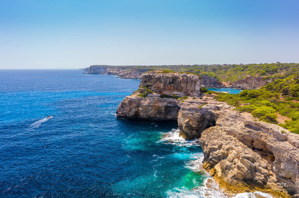 Vibrant coastal cliffs with turquoise sea rocky shore lush greenery and clear blue sky wallpaper