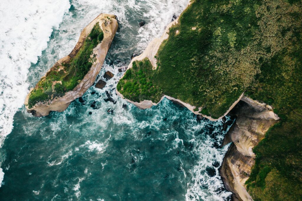 Aerial view of rugged island with green cliffs turquoise sea and dynamic coastal rock formations Wallpaper