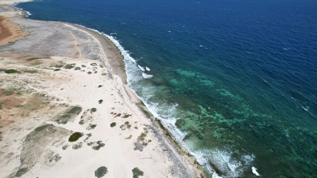 Aerial view of rugged coast with turquoise sea turquoise beach and earthy shoreline wallpaper
