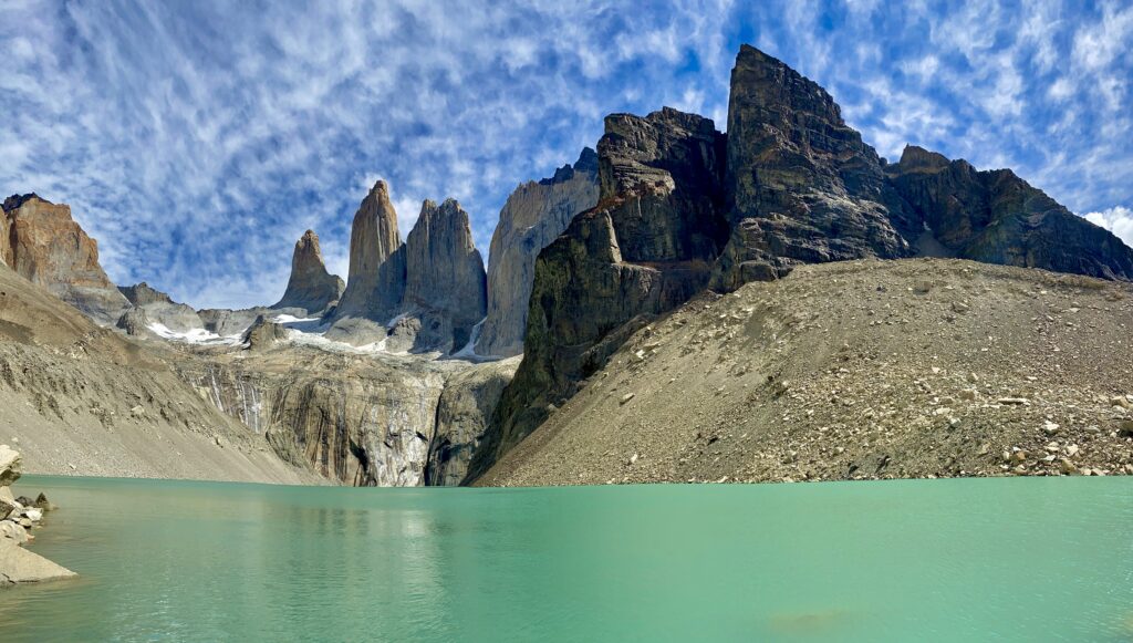 Rugged rocky mountains above turquoise lake with dramatic clouds and vivid blue sky wallpaper