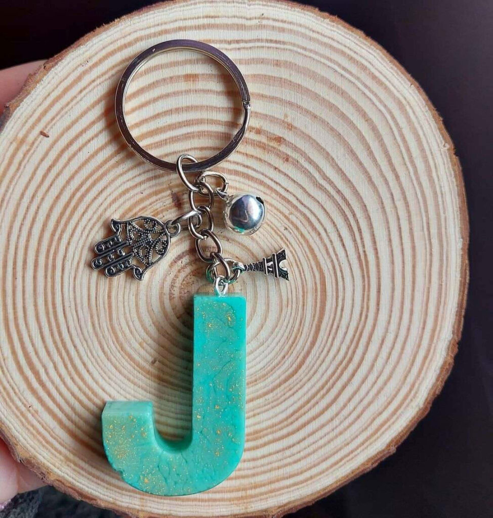 “Turquoise Letter J Keychain with Hamsa Charm on Wooden Background” Wallpaper