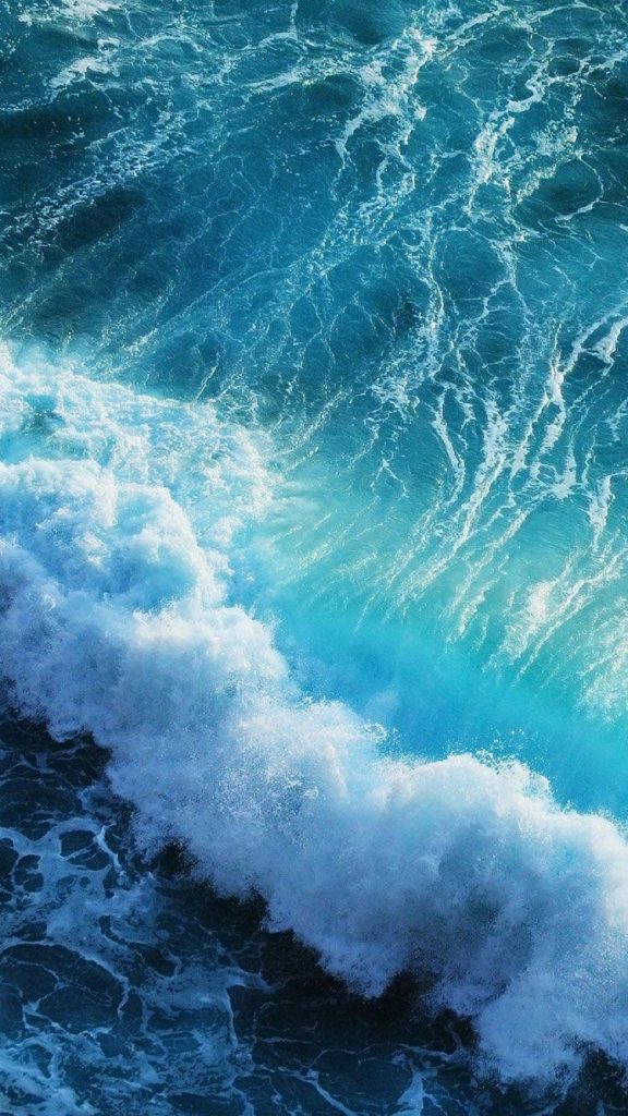 Aerial view of powerful turquoise ocean wave crashing with white sea foam on iPhone wallpaper