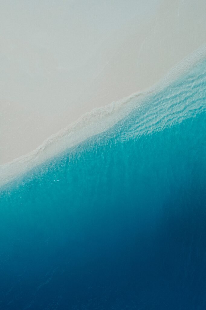 Aerial view of serene beach with turquoise ocean waves and soft sandy shore minimalist wallpaper