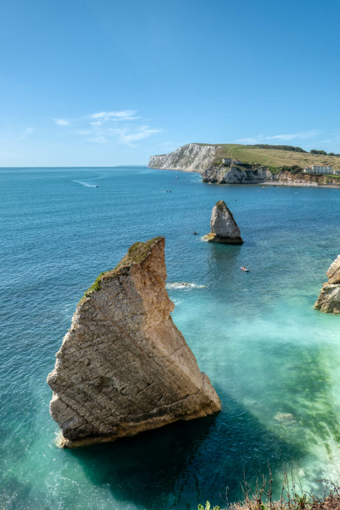 Photorealistic wallpaper of rocky cliffs rising from turquoise sea with boats and vivid blue sky