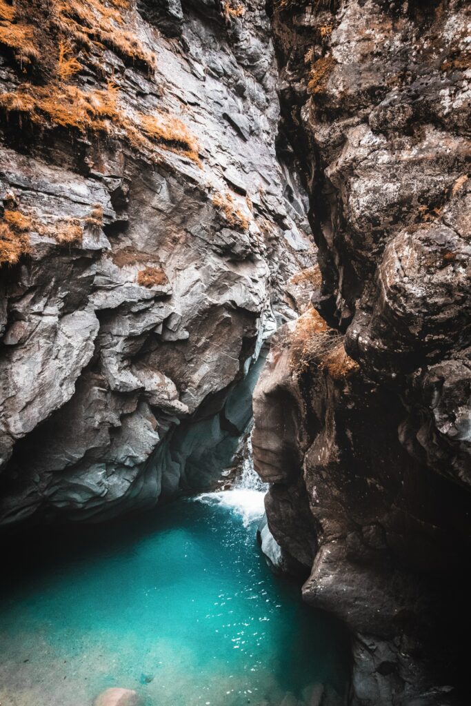 Turquoise water in a dramatic gorge with towering rocky cliffs and lush vegetation wallpaper