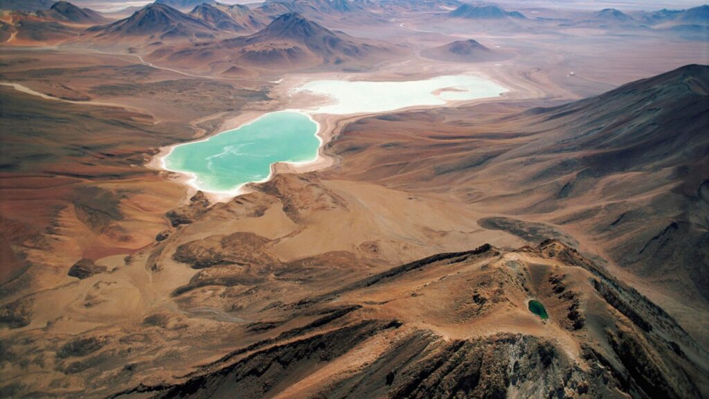 Aerial view of turquoise pools amid rugged mountains and arid landscape natural scenery wallpaper