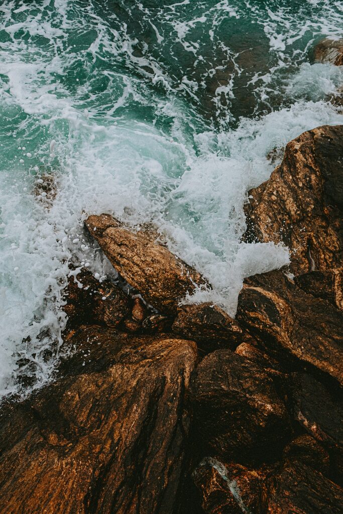 Turquoise waves crashing on rugged brown rocks dynamic water splashes nature wallpaper background