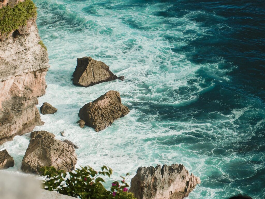 Dramatic turquoise sea waves crashing on rugged stone cliffs vibrant ocean surf wallpaper
