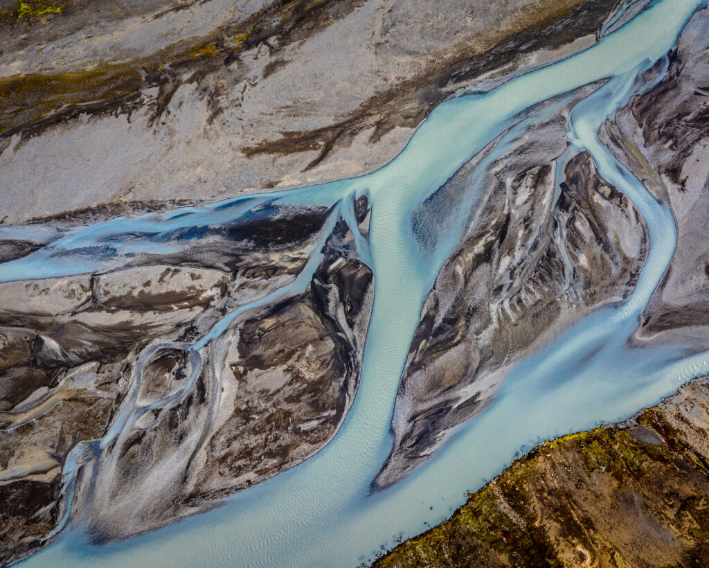 Aerial view of winding turquoise river flowing through rugged earthy banks natural landscape wallpaper