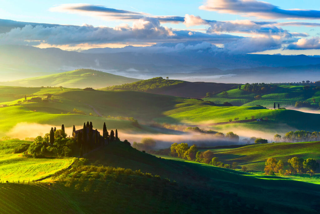Top view of Tuscany rolling green fields with morning fog and scattered trees in soft sunlight Wallpaper