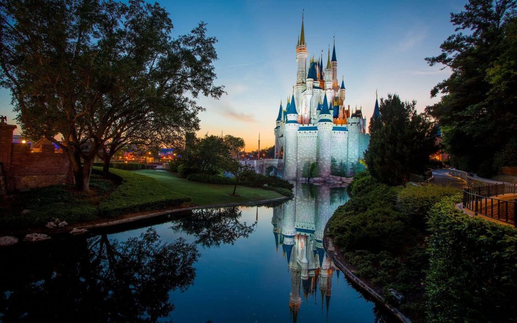 Cinderella Castle glowing at twilight with sunset sky and reflection in Magic Kingdom moat wallpaper