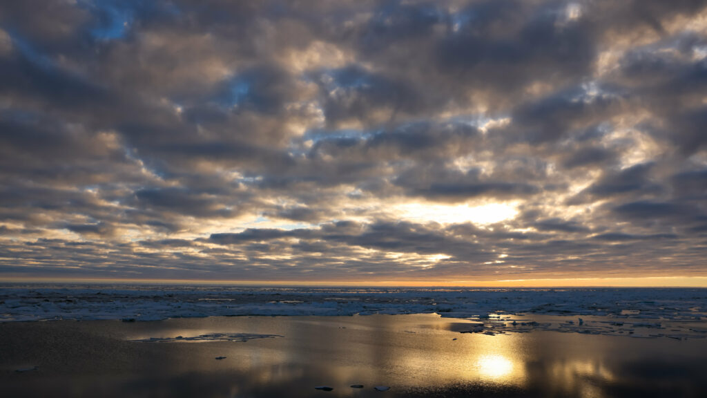 Twilight coastal scene with dramatic clouds warm sunset reflections sand and ice shoreline wallpaper