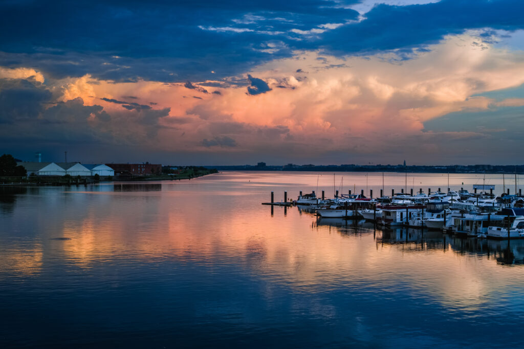 Twilight lakeside view with peaceful pier boats calm water vibrant sunset reflections nature wallpaper