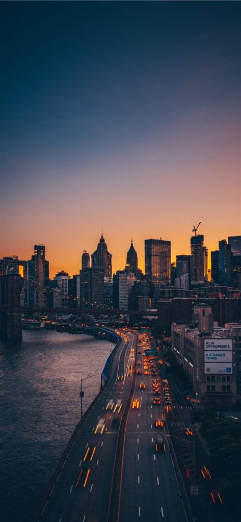 Manhattan skyline at twilight with vibrant sunset and light trails on FDR Drive iPhone wallpaper